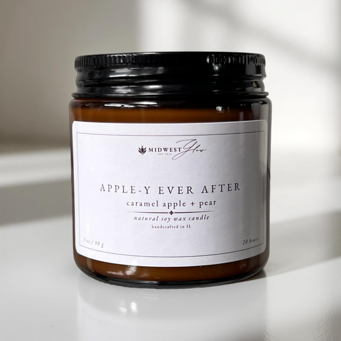 A 3 oz version of the apple-y ever after candle by Midwest Glow sits in front of a white photo backdrop with subtle shadows to showcase the products design
