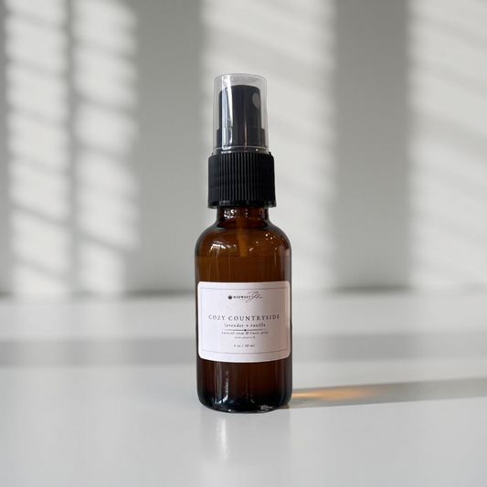 Cozy countryside travel size spray sits against a white photo backdrop with shadows highlighting the product