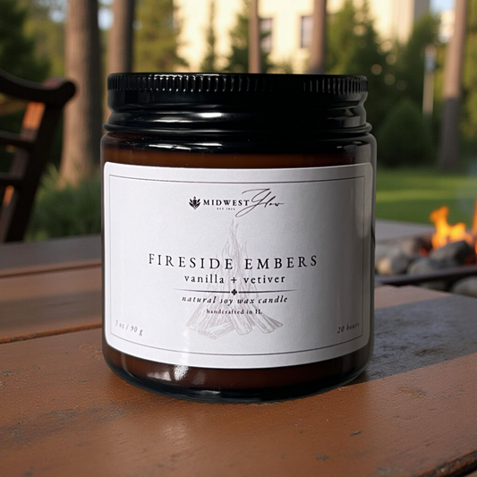 Candle jar labeled 'Fireside Embers' by Midwest Glow on a wooden surface with a blurred outdoor background.