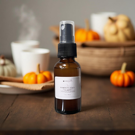 Bottle of pumpkin spice spray on a wooden table with pumpkins and bowls in the background