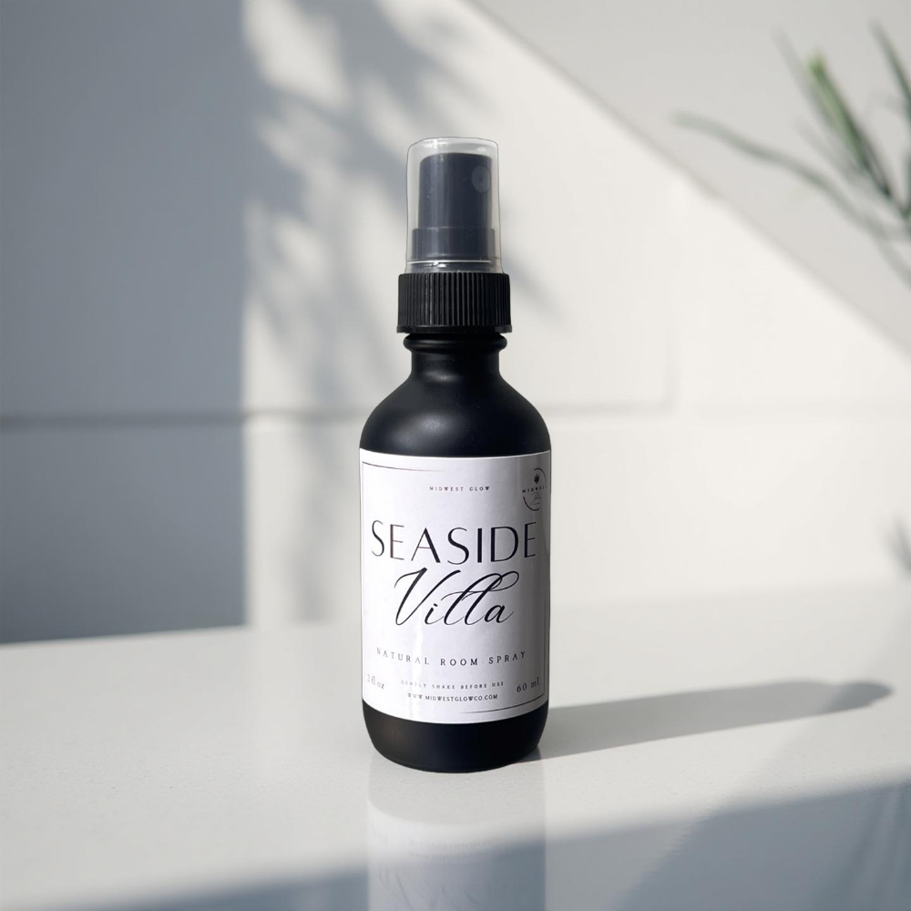 Seaside Villa Room Spray by Midwest Glow sits against a subtle white backdrop with shadows showcasing the product