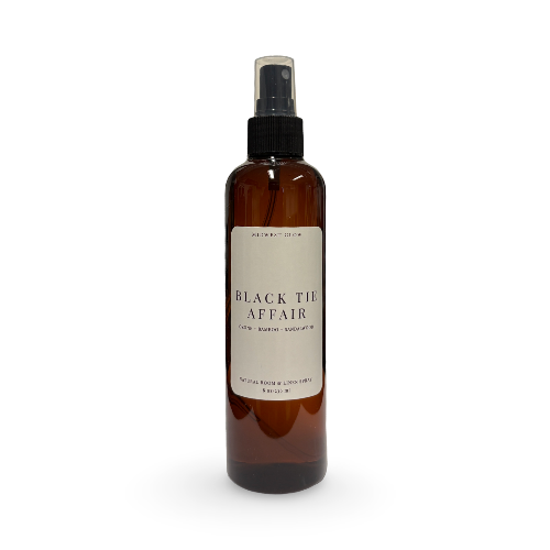 An amber glass spray bottle with a black pump and a cream-colored label reading 'BLACK TIE AFFAIR' on a white background.