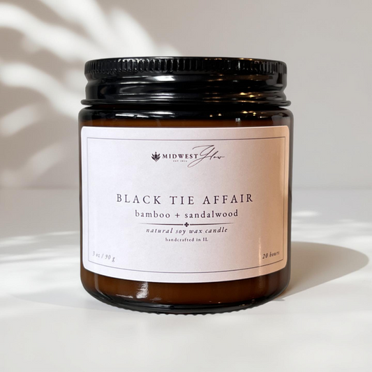 A 3 oz version of the Black Tie Affair candle by Midwest Glow sits against a white photo backdrop with subtle shadows showcasing the products elegant design 