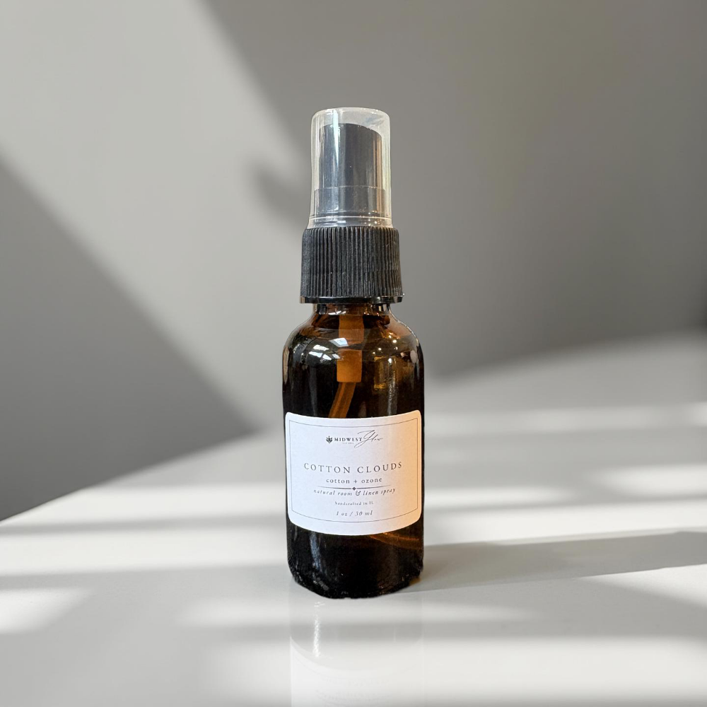 Brown spray bottle with a label on a white surface with shadows