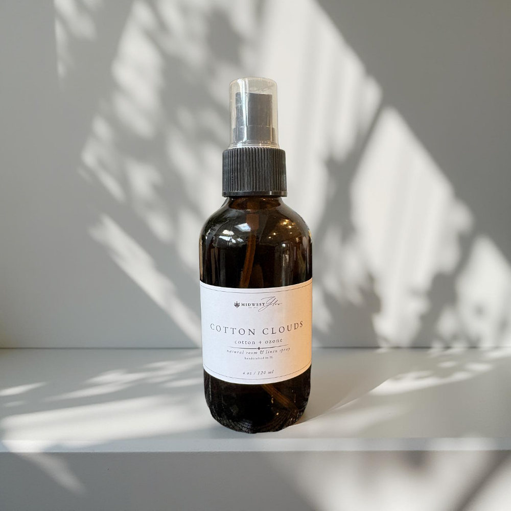 Bottle of 'Cotton Clouds' spray on a white surface with a light background