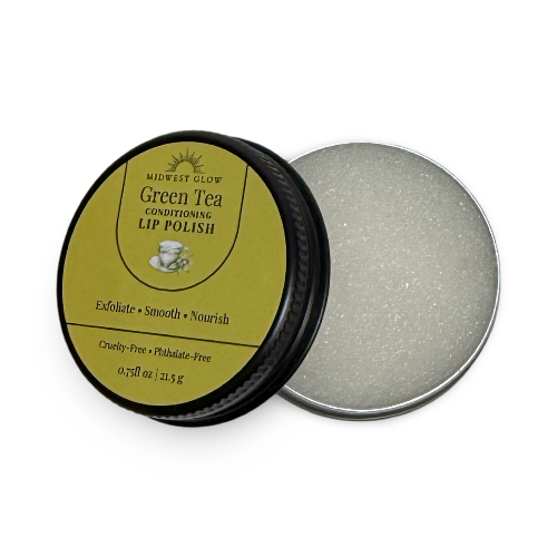 Midwest Glow Green Tea Conditioning Lip Polish in an open round metal tin, showing the black lid with a gold label and the silver-colored lip polish inside.