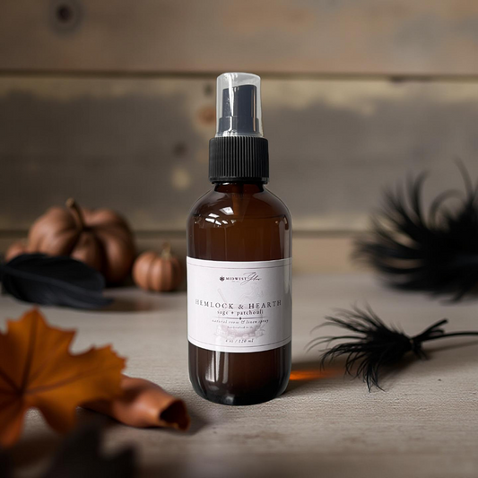 Brown spray bottle with a label on a wooden surface with pumpkins and feathers.