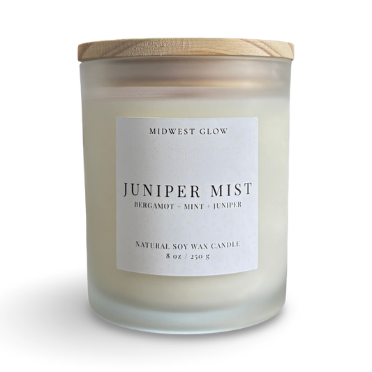 Candle with a wooden lid labeled 'Juniper Mist' by Midwest Glow on a white background