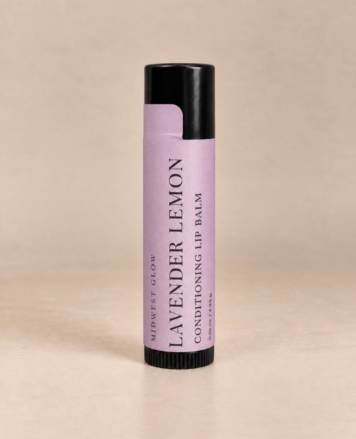 A single tube of Midwest Glow Lavender Lemon Conditioning Lip Balm, featuring a lavender purple label and black cap, set against a solid beige background.