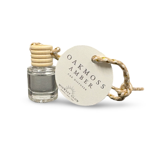 Oakmoss Amber car diffuser with glass container and wooden accents on a white background