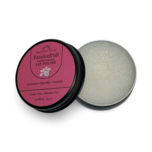 A round metal tin of lip polish shown open, with the pink lid leaning against the container. The label reads 'Miwest Glow Passionfruit Conditioning Lip Polish' and the open tin reveals a pale shimmering cream-colored polish inside.