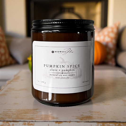 Pumpkin spice candle with a label on a wooden surface, blurred background