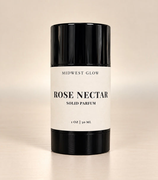 Midwest Glow Rose Nectar Solid Parfum in a black cylindrical container with a white label, set against a warm beige background.