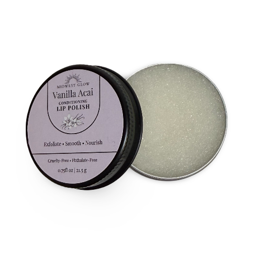 Midwest Glow Vanilla Acai Conditioning Lip Polish in a round silver tin, with the lid showing a lavender label and the open tin displaying a pale acai-colored lip polish with fine glitter.