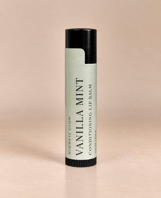 A single tube of Midwest Glow Vanilla Mint Conditioning Lip Balm standing upright on a plain beige background.