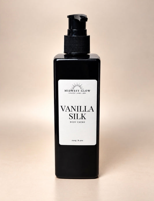 A black rectangular pump bottle of Midwest Glow Vanilla Silk Body Cream with a white label, set against a solid beige background.